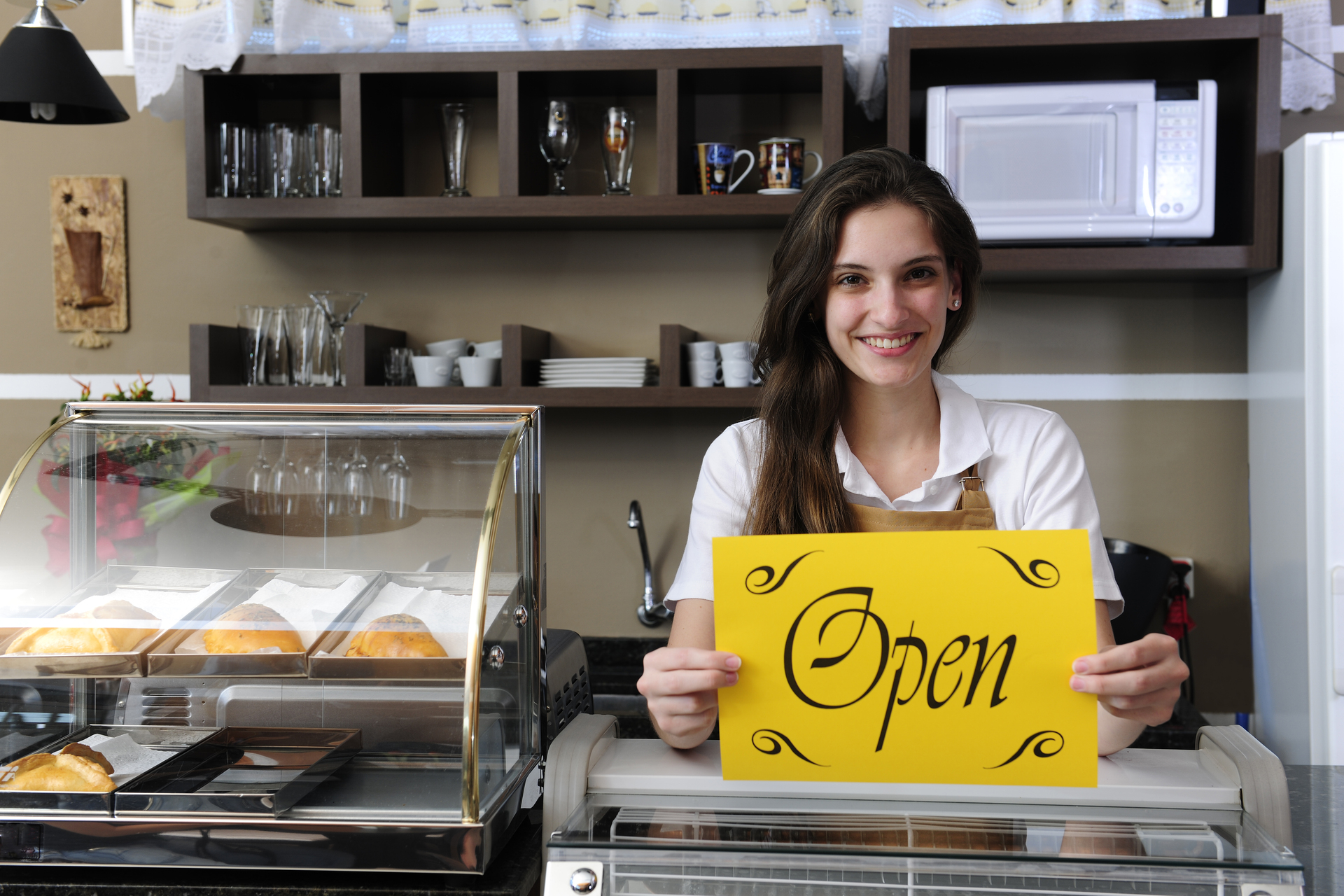 Happy owner of a cafe showing open sign group coaching 1